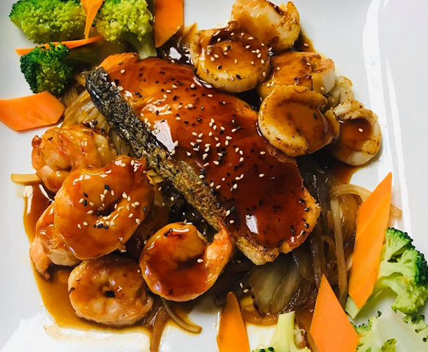 Close up shot of saucy salmon on bed of veggies