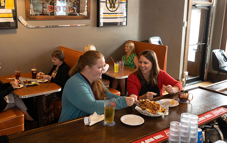 two women sharing food at a bar
